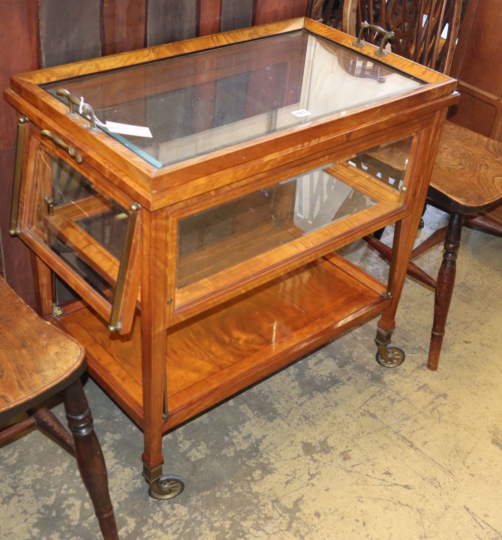 A satinwood three tier trolley, with tray top and glazed upper section, possibly Asprey, W.80cm